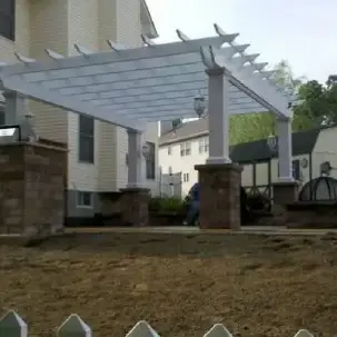 White pergola with stone columns in a backyard under construction