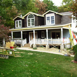 Large house undergoing exterior renovations with a porch and scaffolding